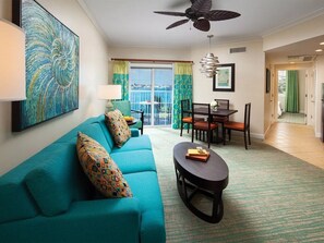 A living room with a teal sofa, a round coffee table, and a dining area with a table and chairs. - Harborside at Atlantis – Premium 2-Bedroom Villa with Full Resort Access (N.P)