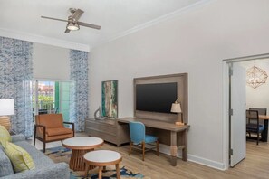 A modern living room with a flat-screen TV, a desk, and a sofa. - Harborside at Atlantis – Premium 2-Bedroom Villa with Full Resort Access (N.P)