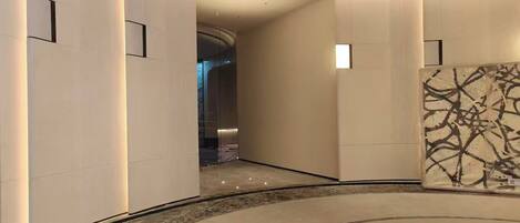 A modern lobby with curved walls, recessed lighting, and a central circular seating area.