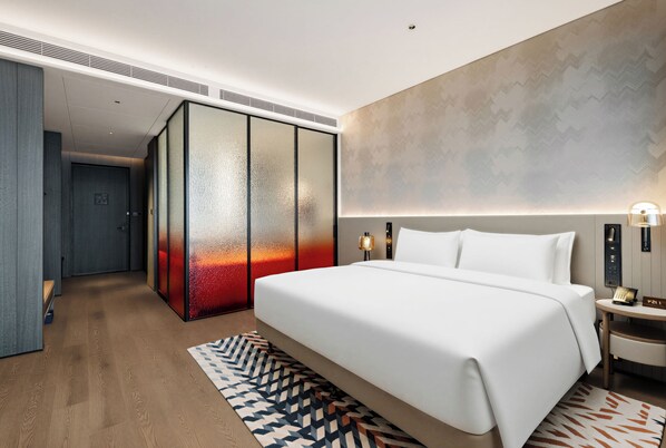 Une chambre d’hôtel moderne dotée d’un grand lit, d’un dressing et d’un téléphone fixé au mur.