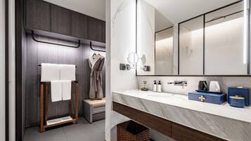 A modern bathroom with a marble vanity, a large mirror, and a towel rack.