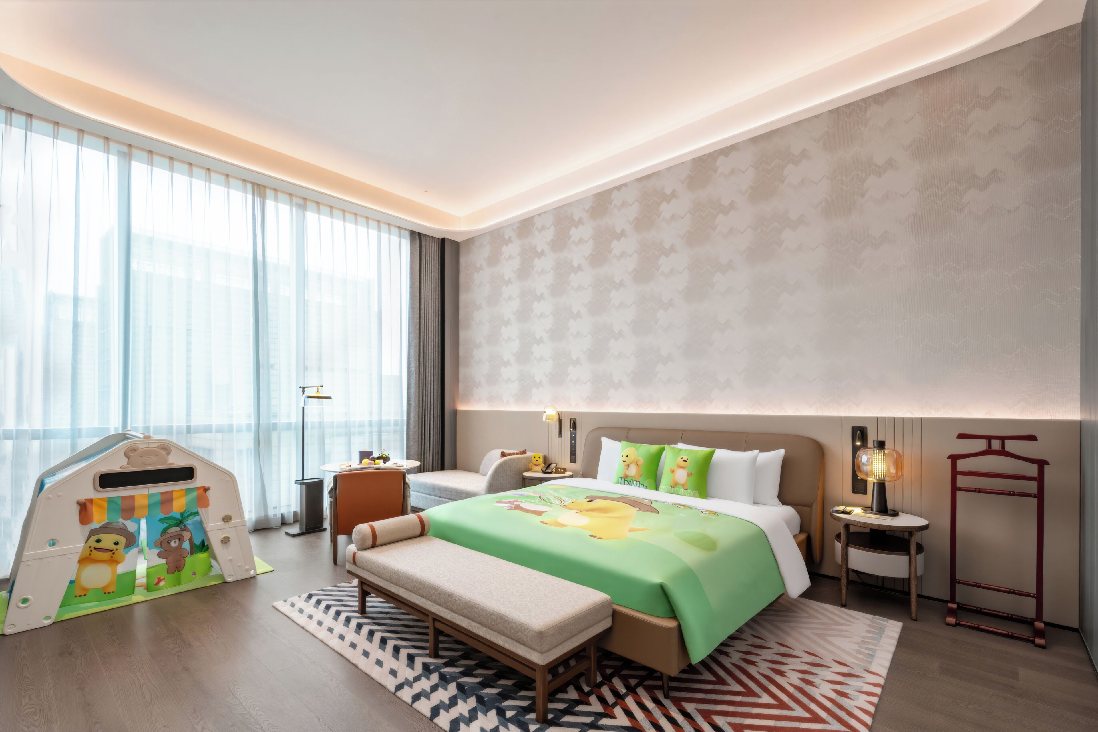 Una habitación de hotel moderna con cama, banca, escritorio, lámpara y ventana con cortinas.