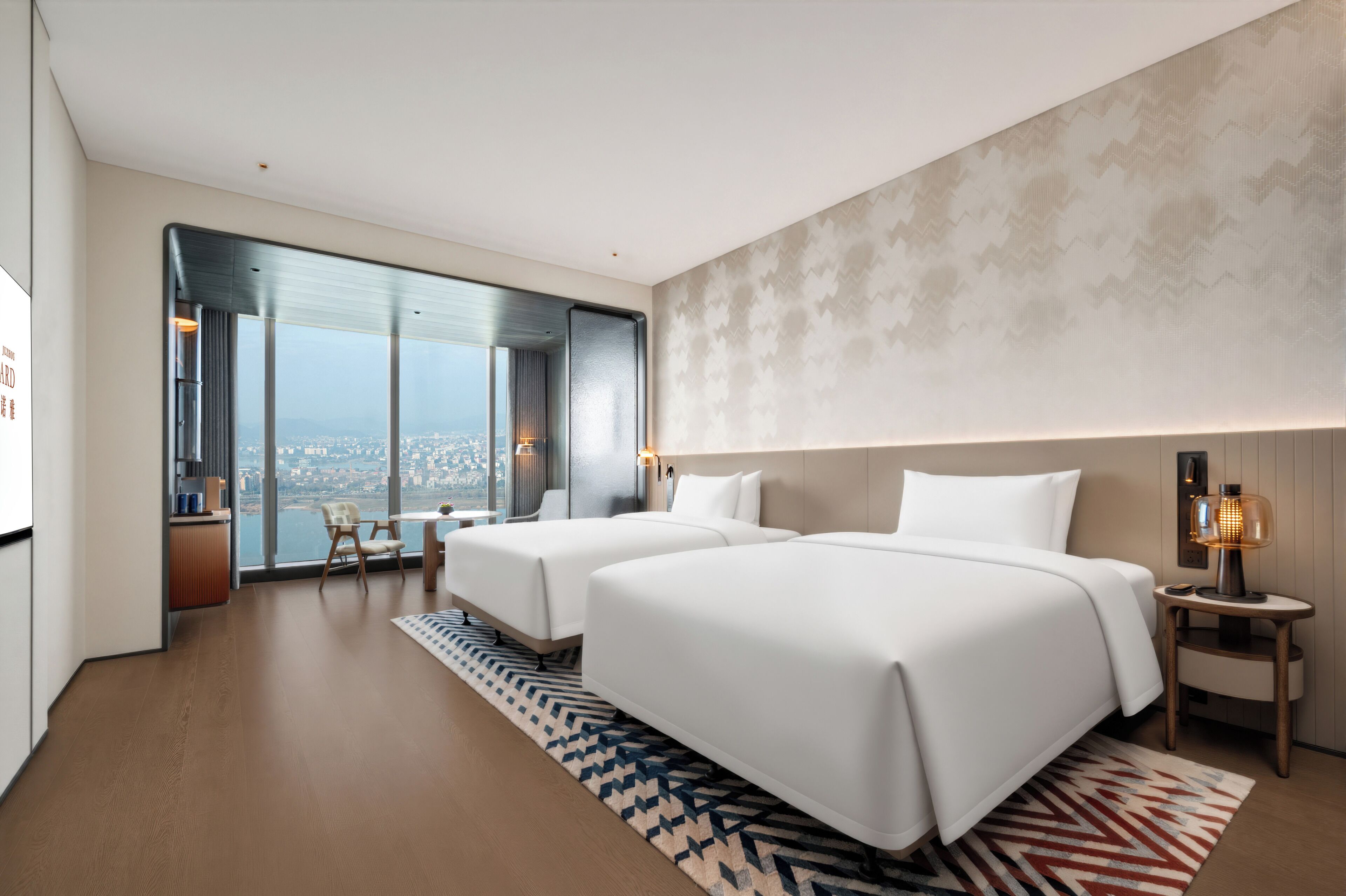 A modern hotel room with two beds, a view of the city, and a large window.