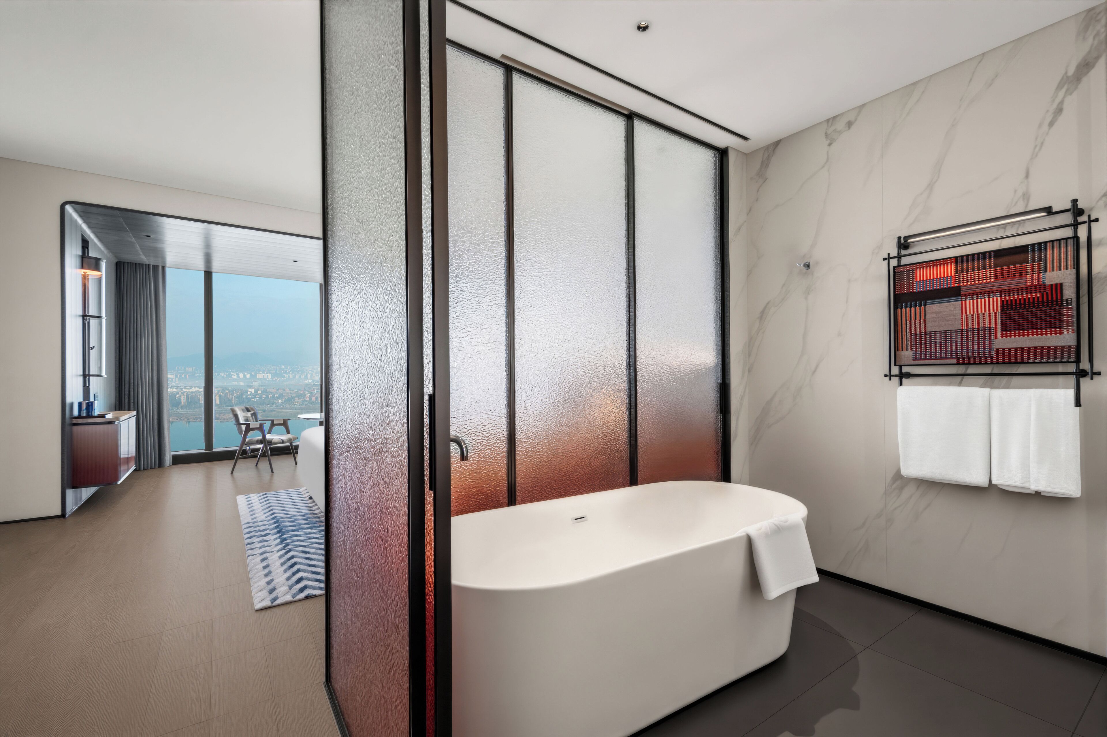 Ein modernes Badezimmer mit freistehender Badewanne, einer Glasdusche und Blick auf die Stadt.