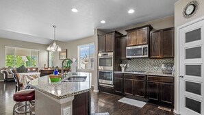 Una cocina moderna con armarios de madera oscura, electrodomésticos de acero inoxidable y una isla grande con taburetes.