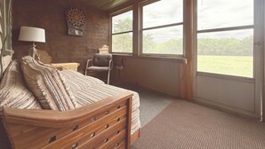 A room with a bed, a chair, a lamp, a dartboard, and large windows. - Country Farmhouse on a Working Cattle Ranch (El Dorado)