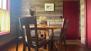 A wooden dining table with chairs, a framed picture, and a mirror on the wall. - Country Farmhouse on a Working Cattle Ranch (El Dorado)