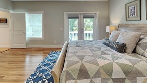 Une chambre à coucher avec un lit, un ventilateur de plafond, une fenêtre avec des stores et une porte.