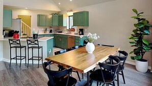 Uma cozinha moderna com armários verdes, uma mesa de jantar de madeira e cadeiras pretas.