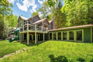 A two-story house with a green exterior, a covered porch, and a slide. - Copper Canoe (Oakland)