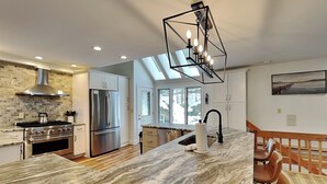 A modern kitchen with a marble island, stainless steel appliances, and a skylight. - Copper Canoe (Oakland)