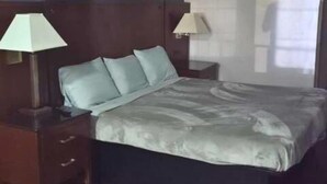 Quarto de hotel com uma cama grande, duas mesas de cabeceira e duas luminárias.