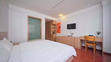 A modern bedroom with a large bed, a desk, a chair, and a television.