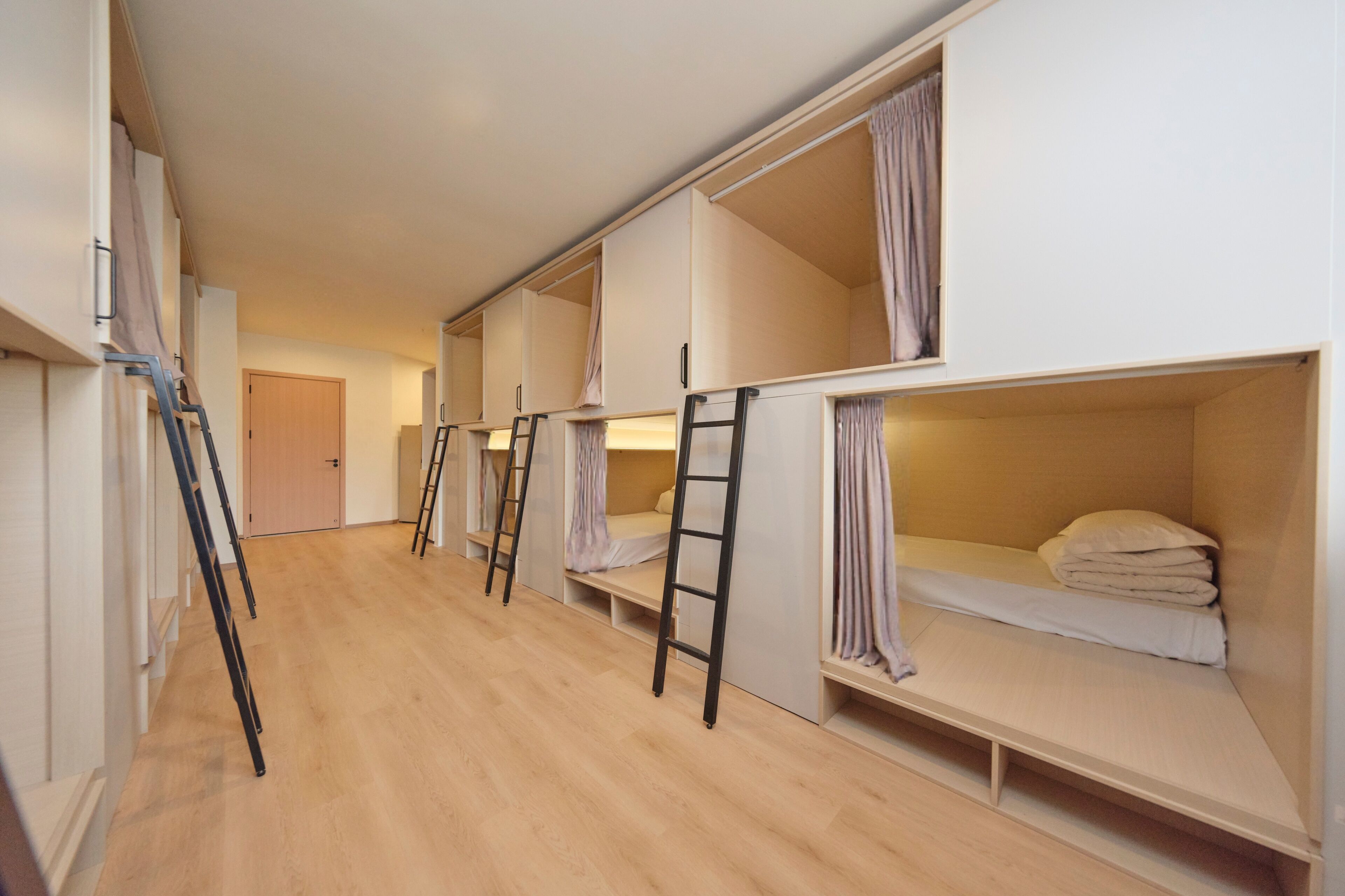 Un dormitorio con literas, piso de madera y una escalera.