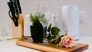 A kitchen counter with a cutting board, a glass of water, a potted plant, a rose, and a coffee maker. - French home walking to shops and shopping center (Maidstone)