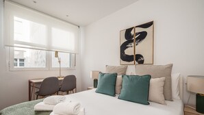 Ein Hotelzimmer mit einem Bett, zwei Sesseln, einem Schreibtisch und einem Fenster.