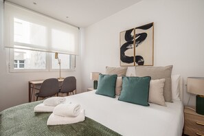 Une chambre d’hôtel avec un lit, deux chaises, un bureau et une fenêtre.