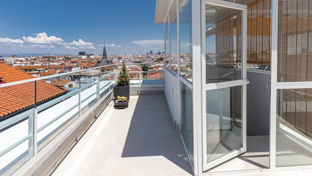 Ein Balkon mit Blumentopf, Glastüren und Blick auf die Stadt.