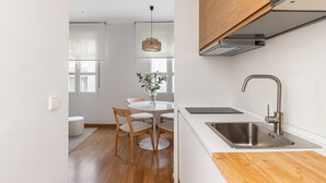 Eine moderne Küche mit Spüle aus Edelstahl, einer Holz Arbeitsplatte und einem runden Esstisch mit Stühlen.