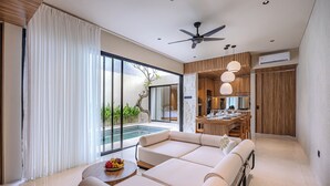 Un salon moderne avec un canapé, une table à manger et une vue sur une piscine et un espace verdoyant.