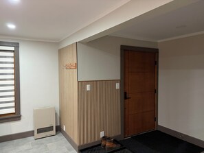 A hallway with a radiator, a door, and a shoe rack. - Private Modern Adirondack Home (Saranac Lake)