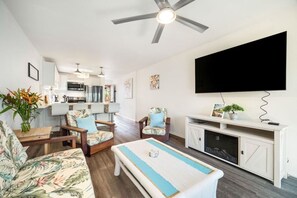 A living room with a sofa, chairs, a coffee table, a television, and a fireplace. - Just Listed! Banyan Retreat at Kalapaki Bay Beach (Lihue)