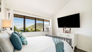 Una camera da letto con un letto, una finestra vista, una TV a schermo piatto e un comò.