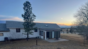 Uma casa moderna com um amplo pátio, área de estar coberta ao ar livre e vista para a paisagem circundante.