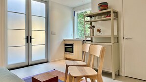 A modern kitchen with a built-in oven, a wooden chair, and a shelf with kitchenware. - Cozy 1-bedroom beach bungalow in beautiful Encinitas 1 block from surf with AC (Encinitas)