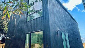 A modern building with a dark exterior, large windows, and a visible door. - Cozy 1-bedroom beach bungalow in beautiful Encinitas 1 block from surf with AC (Encinitas)