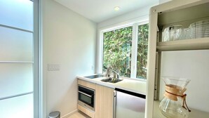 A modern kitchen with a window, stainless steel appliances, and a clear view of greenery outside. - Cozy 1-bedroom beach bungalow in beautiful Encinitas 1 block from surf with AC (Encinitas)