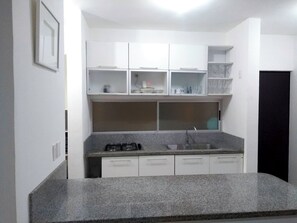 A compact kitchen with white cabinets, a granite countertop, and a gas stove. - Punta Estrella apartment complete 2 bedrooms AC WiFi (Playa Del Carmen)