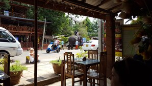 A restaurant with outdoor seating, a signboard, and a street view with vehicles and pedestrians. - Nilmini Lodge (Sigiriya)