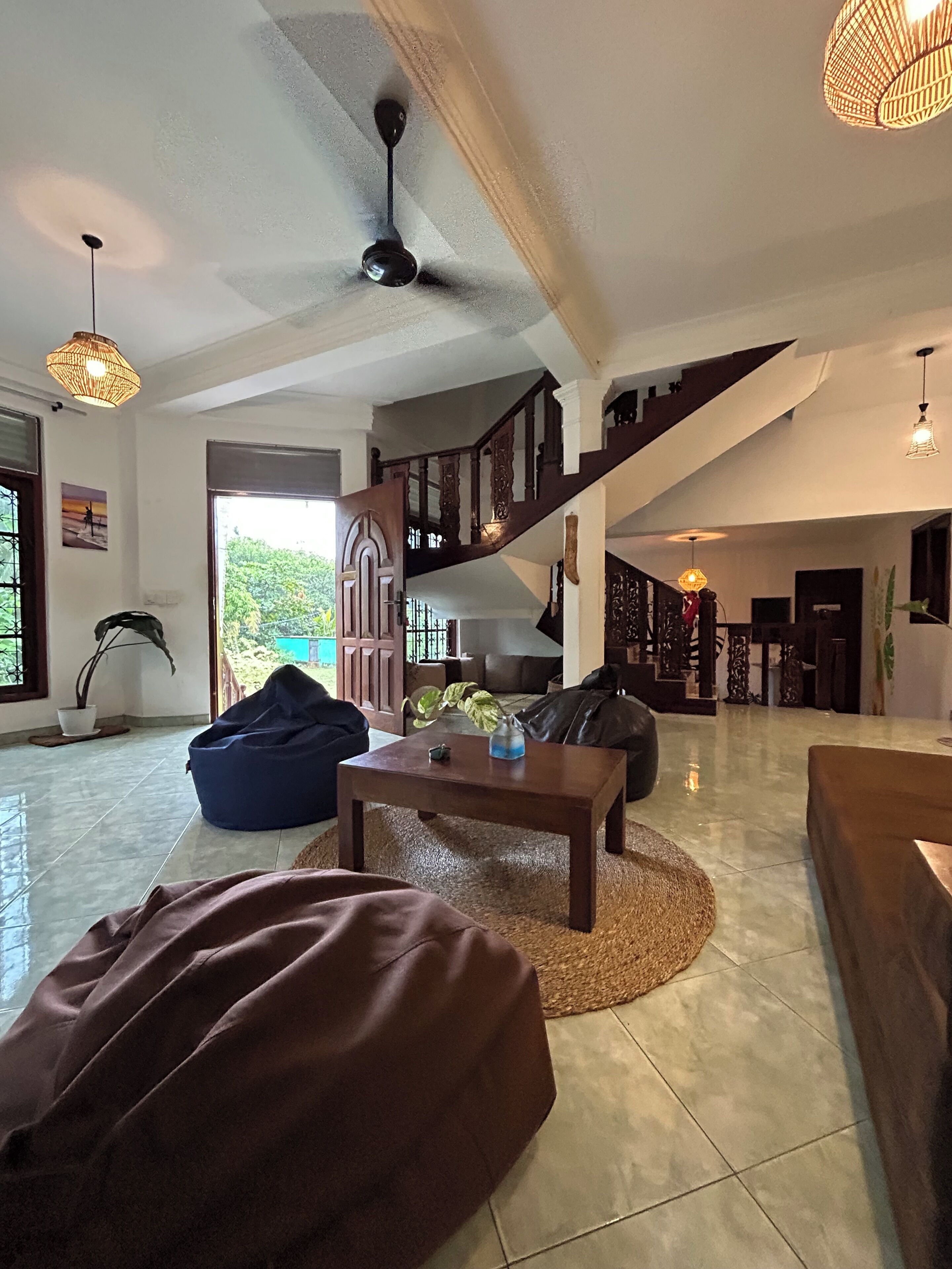A spacious living area with a staircase, a ceiling fan, and a view of the outdoors.