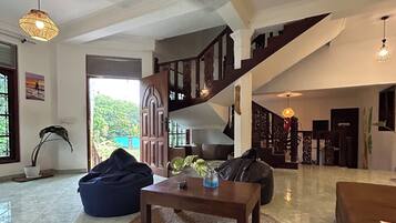A spacious living area with a staircase, a ceiling fan, and a view of the outdoors.
