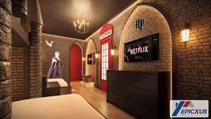 Ein Hotelzimmer mit Backsteinwand, einer roten Telefonzelle, einem Netflix-Schild und einer Chandelier.