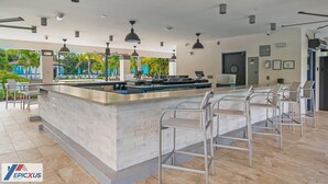 Eine moderne Bar mit einer zentralen Theke, Barhocker und Pendelleuchten.