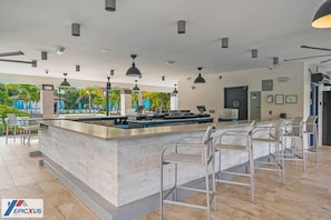 A modern bar area with a central counter, bar stools, and pendant lighting. - The Epic 04304 Lake View Vista Cay Resort Orlando Florida (Orlando)