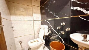 Ένα μπάνιο με τουαλέτα, νιπτήρα και έναν κουβά.