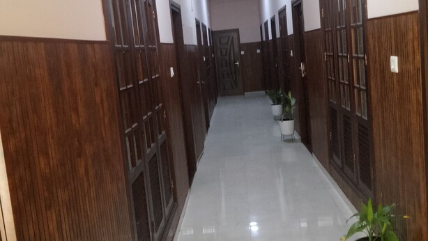 A hallway with wooden paneling on the walls, a tiled floor, and potted plants. - Holidayhomecochin  (Kanayannur)