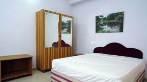 A bedroom with a bed, a wardrobe, and a small table. - Holidayhomecochin  (Kanayannur)