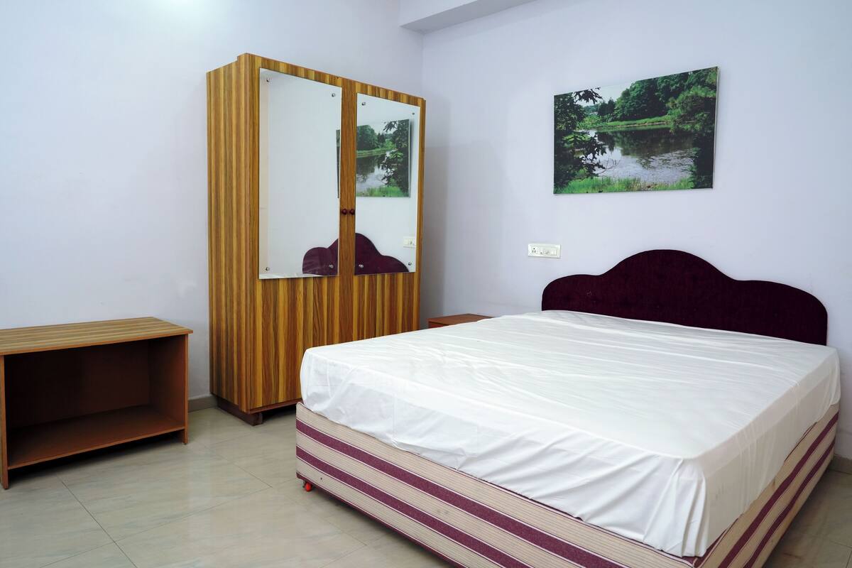 Un dormitorio con cama, armario y una mesita.