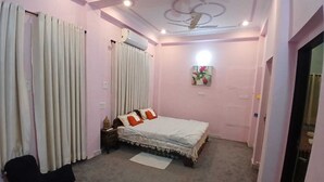 Une chambre à coucher avec un lit, des rideaux, une table de chevet, une lampe et un ventilateur de plafond.