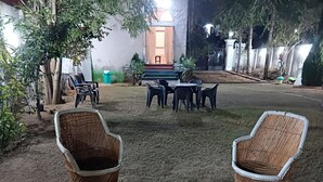 Un espace extérieur aménagé avec des chaises en osier et un foyer central.