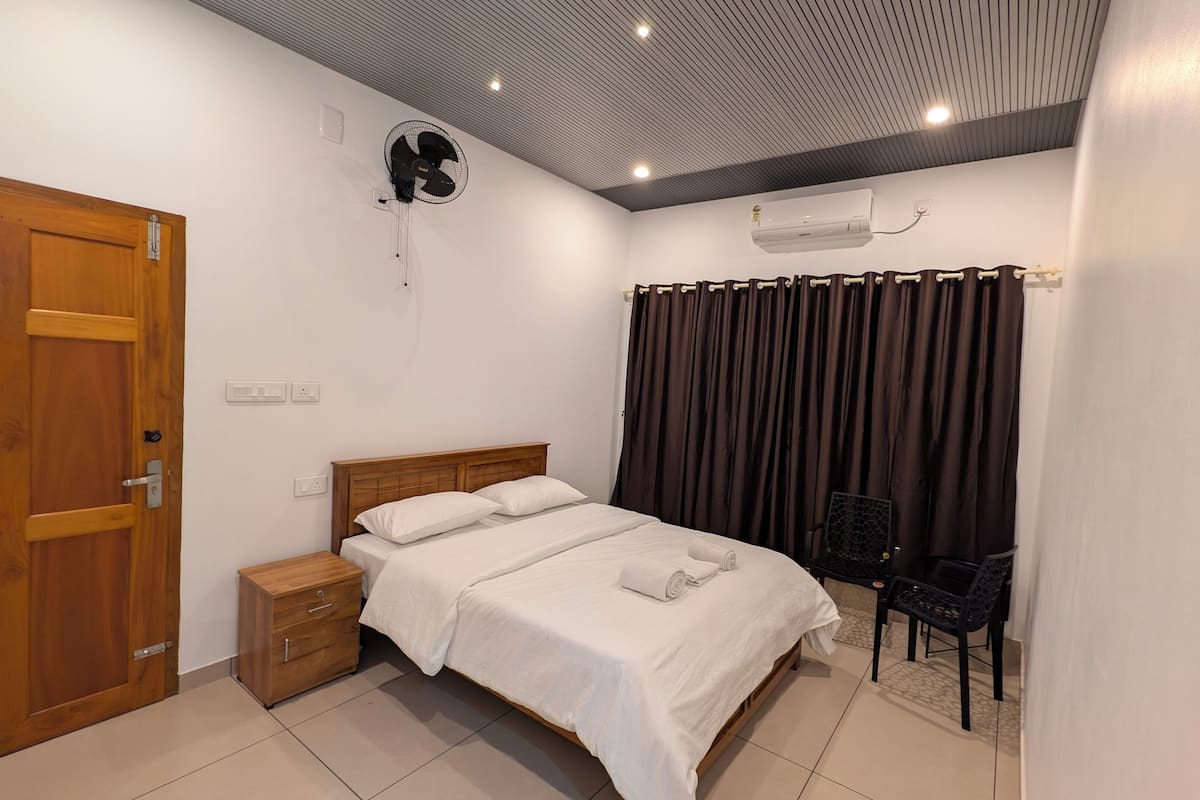 A bedroom with a wooden bed, bedside table, and a ceiling fan.