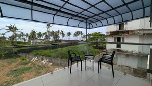 Un balcon doté d’une paroi vitrée, de deux chaises et d’une petite table.
