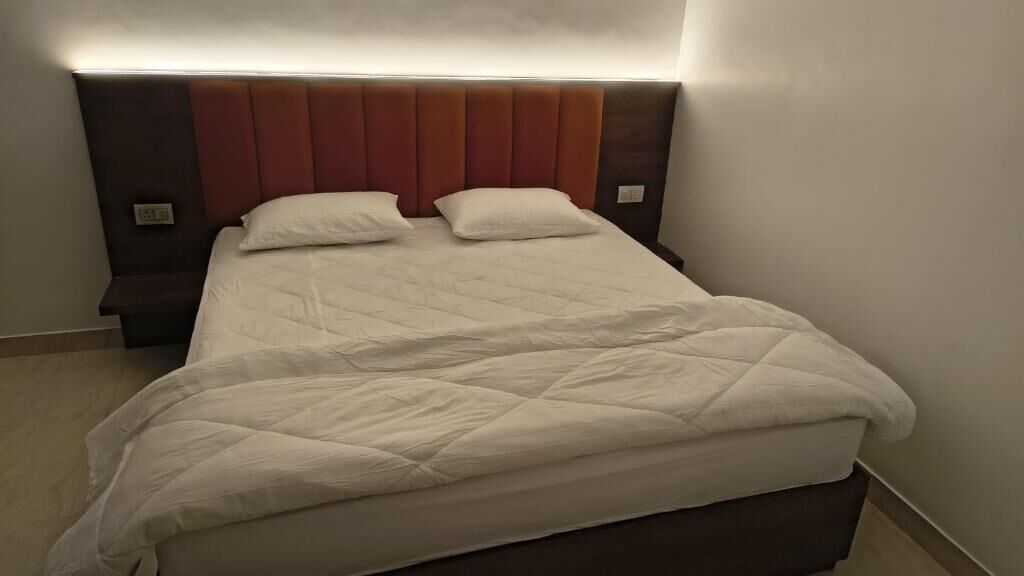 Un lit bien fait, avec une couverture matelassée, une tête de lit rembourrée et des lampes de chevet.