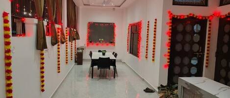 A hallway with a dining table and chairs, a potted plant, and a reception desk.