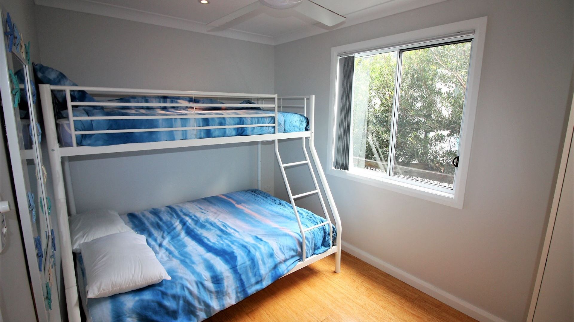 A bunk bed room with a window and a wooden floor.