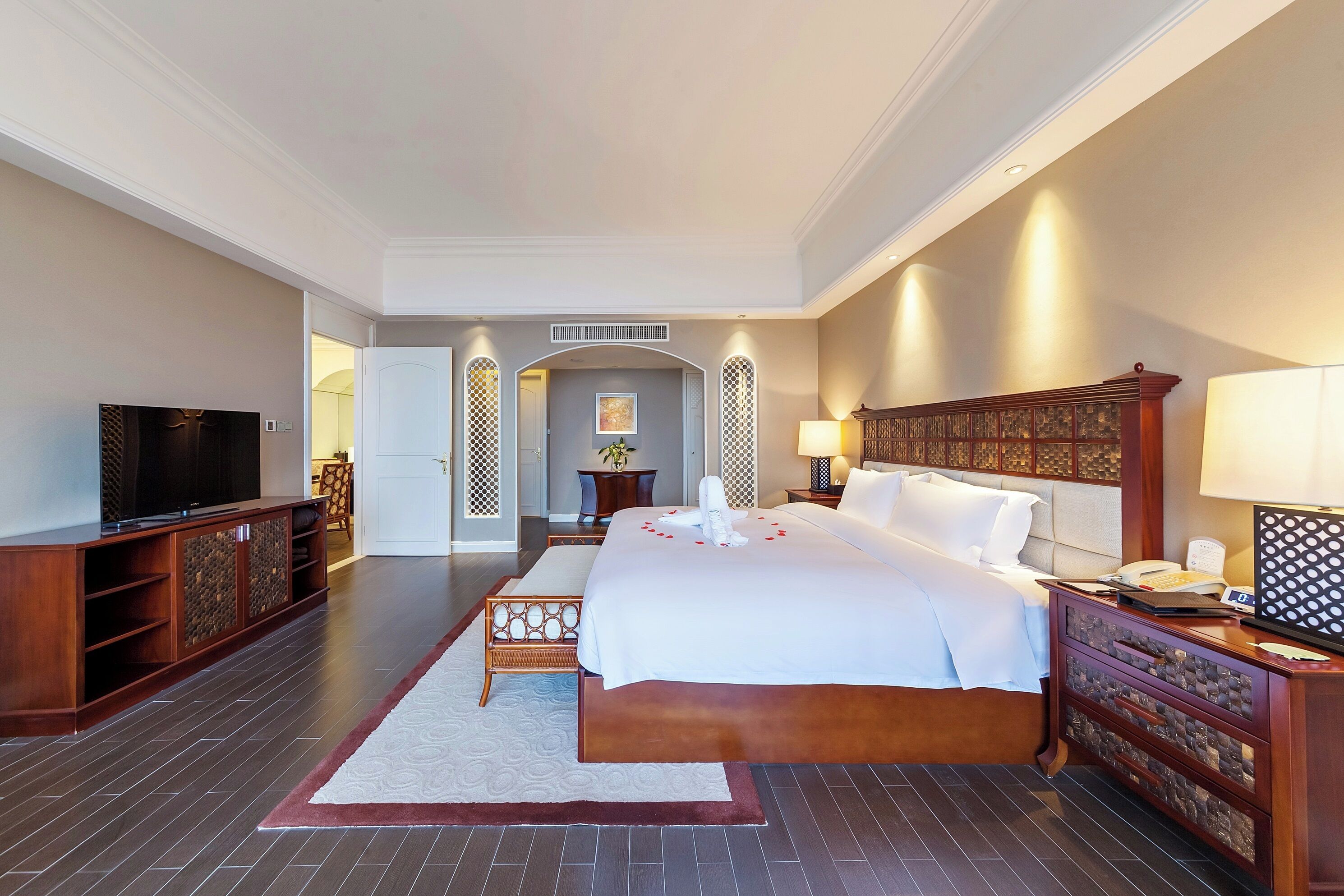 A hotel room with a large bed, a television, a desk, and a chair.